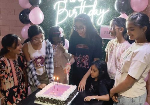Kids celebrating a birthday party at Lock N Escape with balloons, cake, and decorations, smiling together around the birthday cake.
