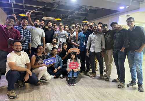 A group of employees smiling and holding escape room victory signs after completing a team-building challenge at Lock N Escape corporate event.