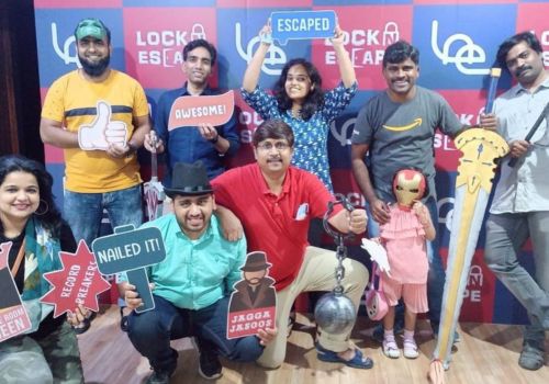 A group of friends posing with fun props and signs after completing an escape room challenge at Lock N Escape group event.