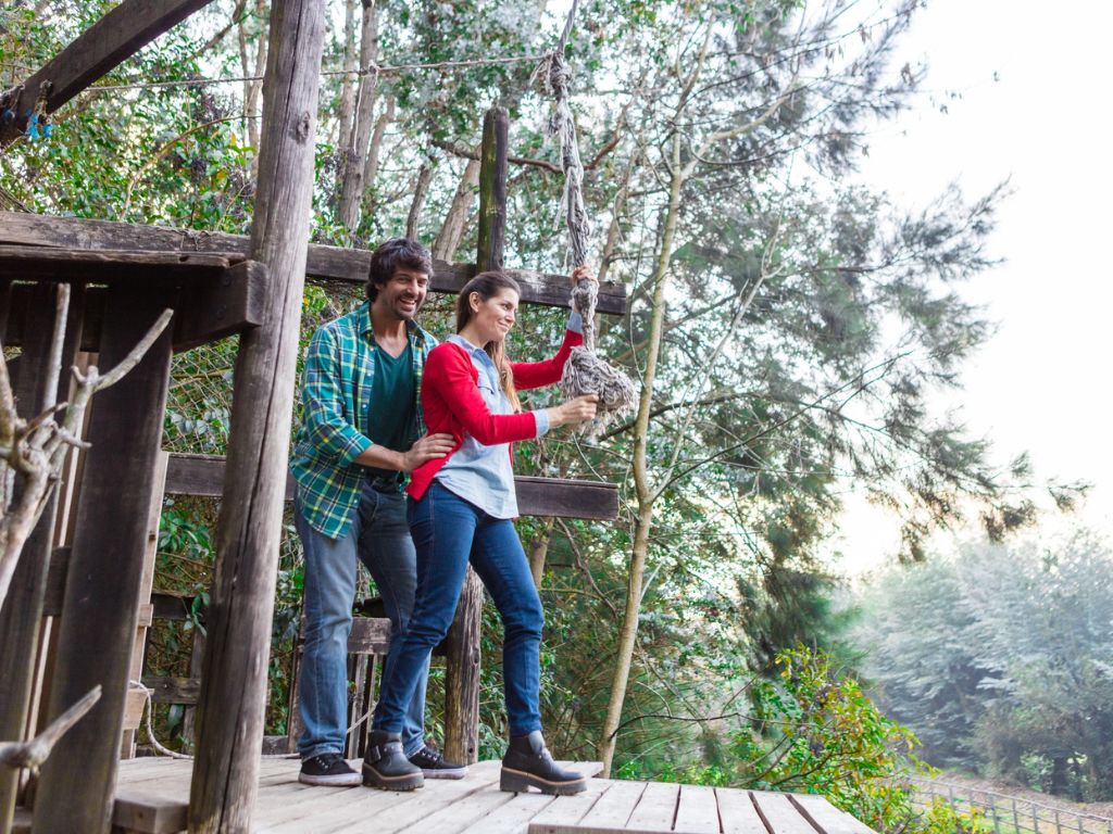 Adventure & Thrill Parks for corporate team outings in Hyderabad — two colleagues on an outdoor rope activity platform surrounded by trees