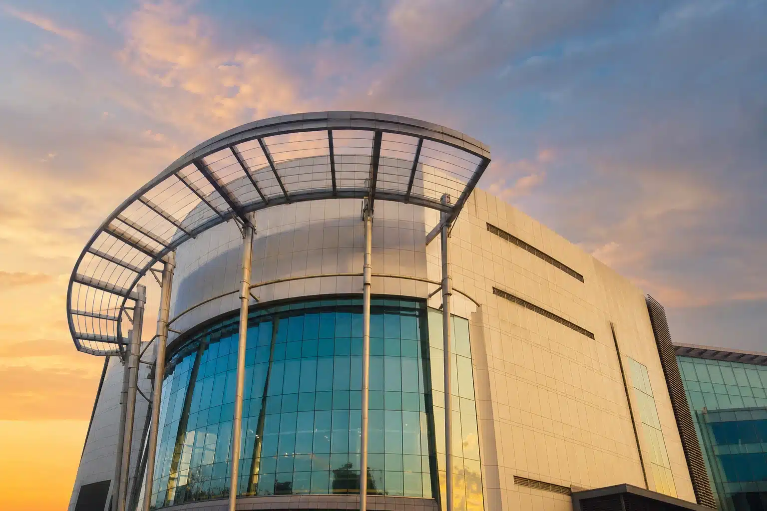 A modern glass-fronted shopping mall at sunset